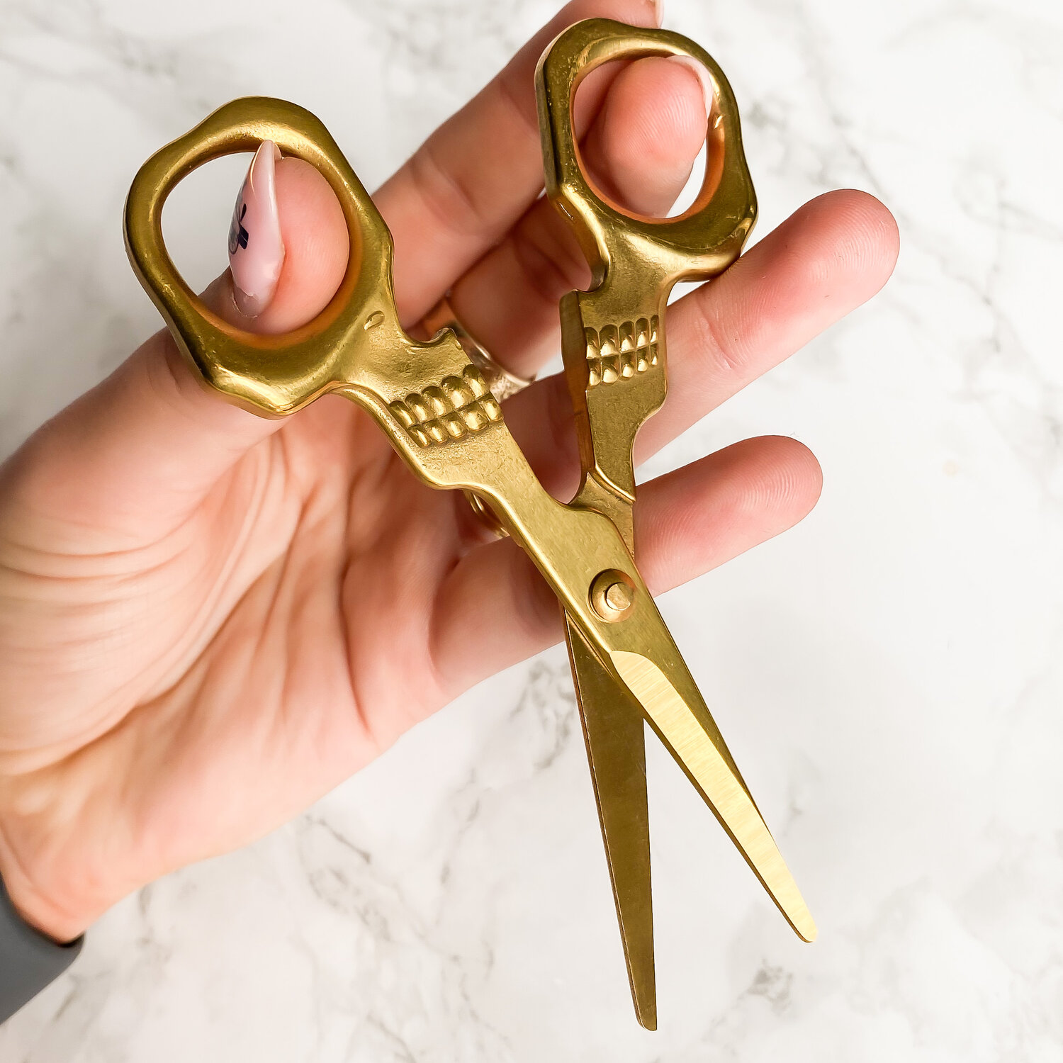 a hand holding a golden scissors